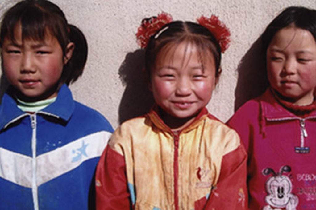 Three elementary school students smiling at the camera